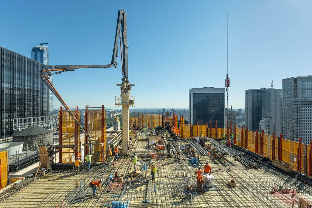 A concrete pump boom reaches over the deck reinforcement, perimeter screens up