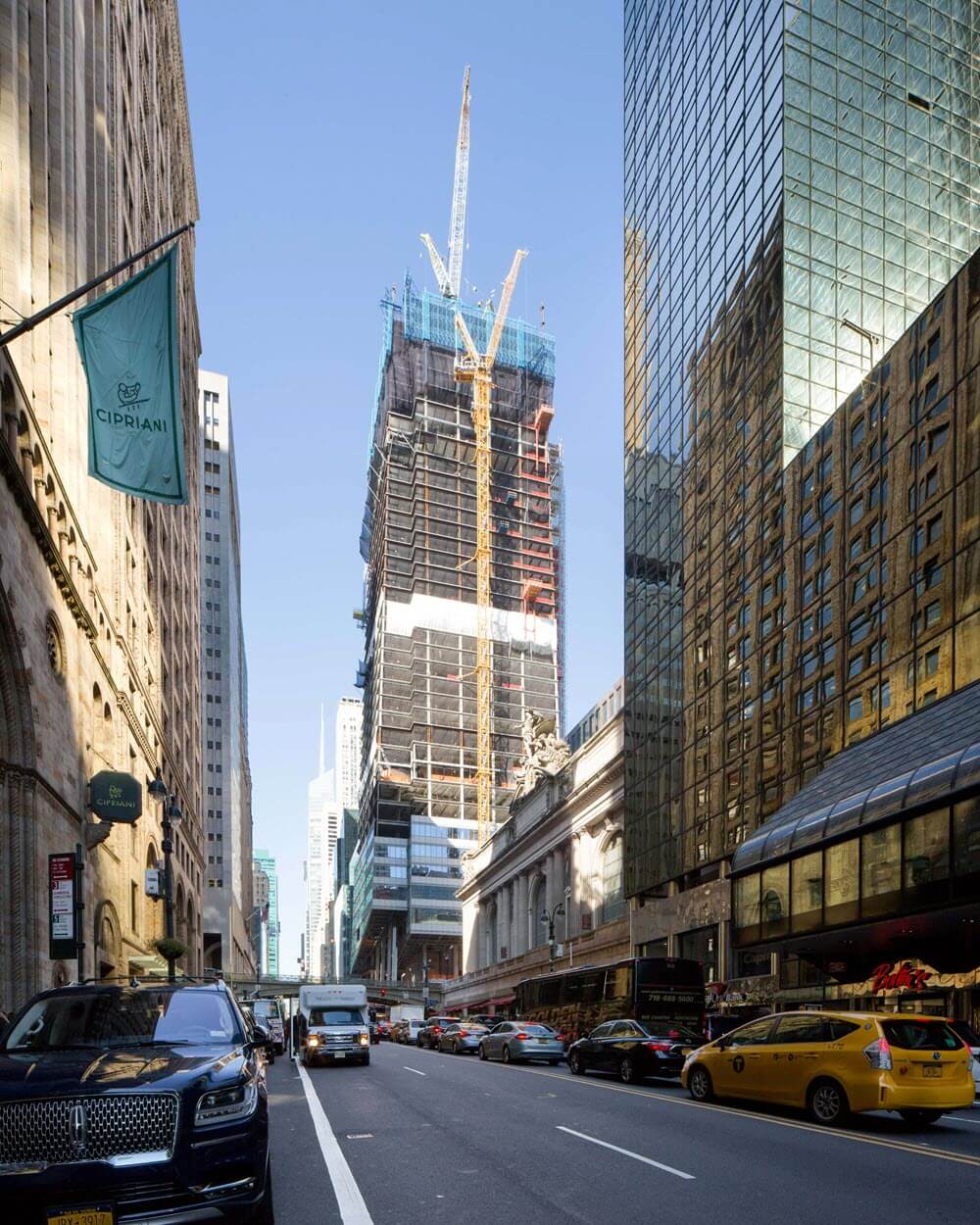 The tower climbs over the street, a crane working at the top
