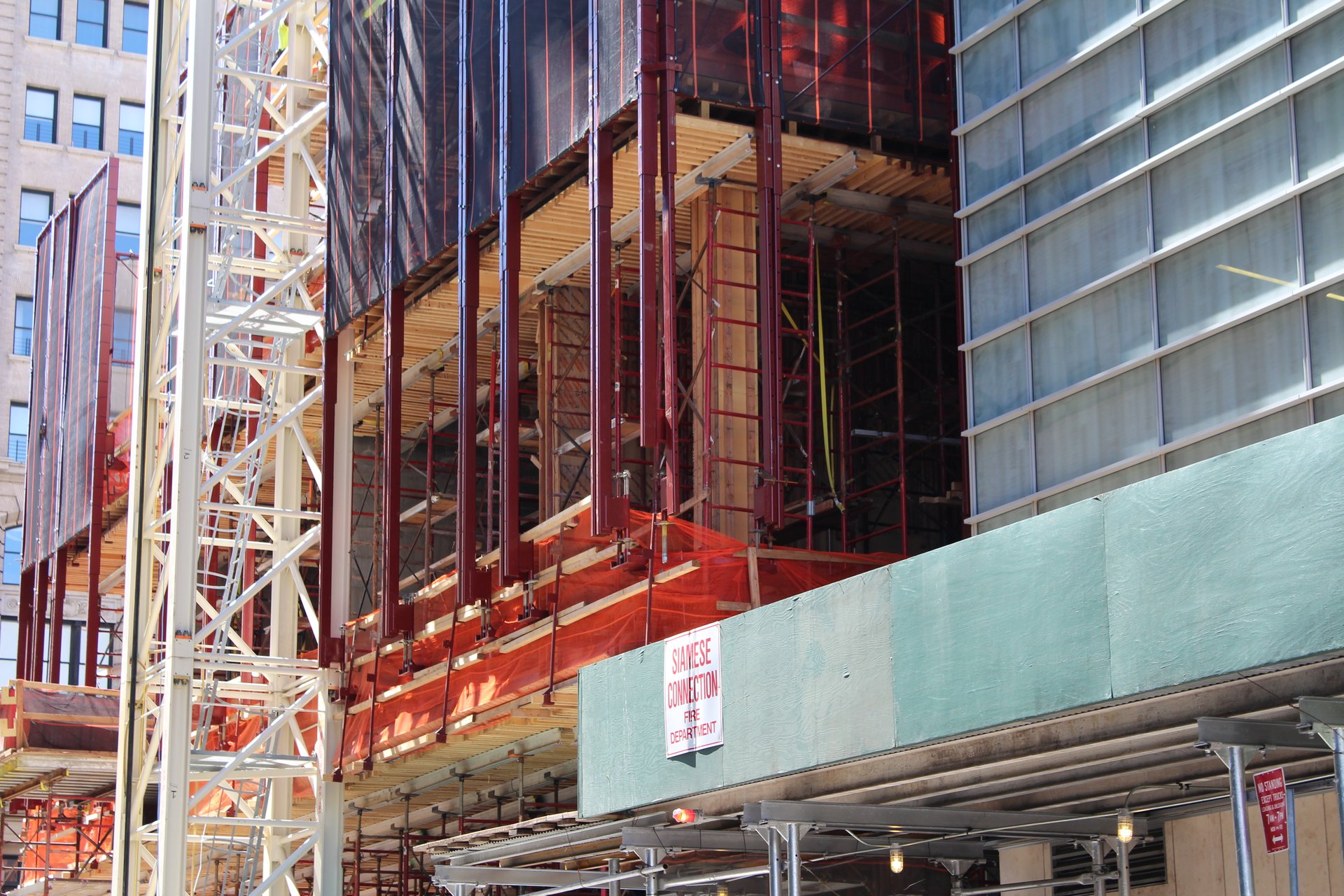 Protective netting and perimeter screens wrap the rising floors above the sidewalk shed
