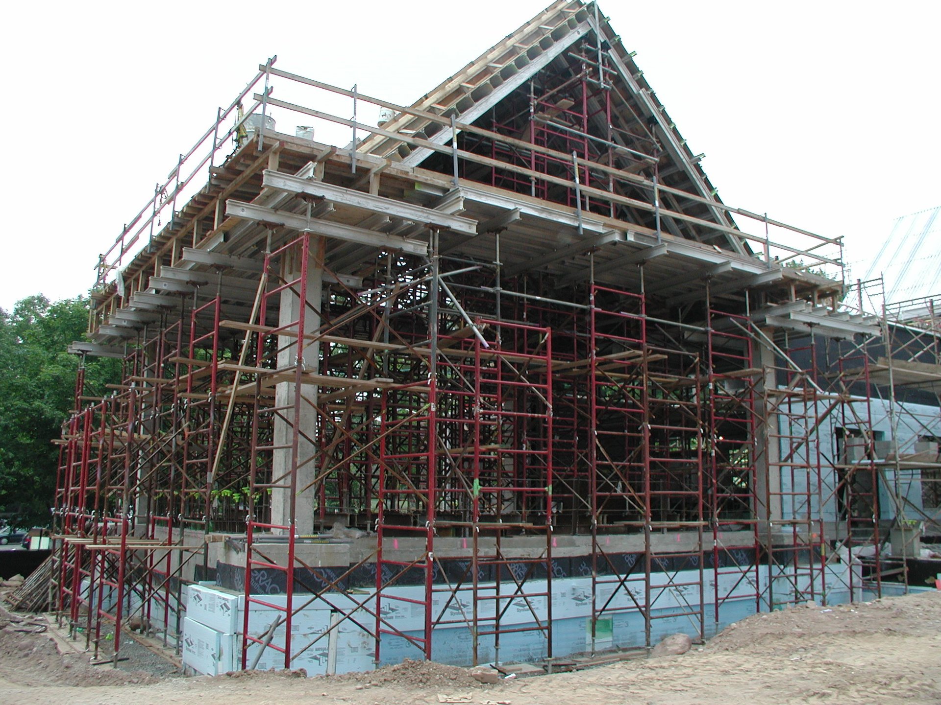 Frame shoring towers wrap the corner of the gable structure