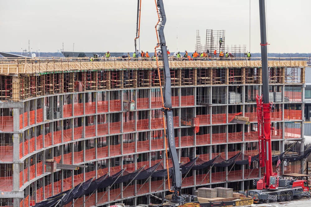Formwork lines the curved face as crews work the top deck, pump boom overhead